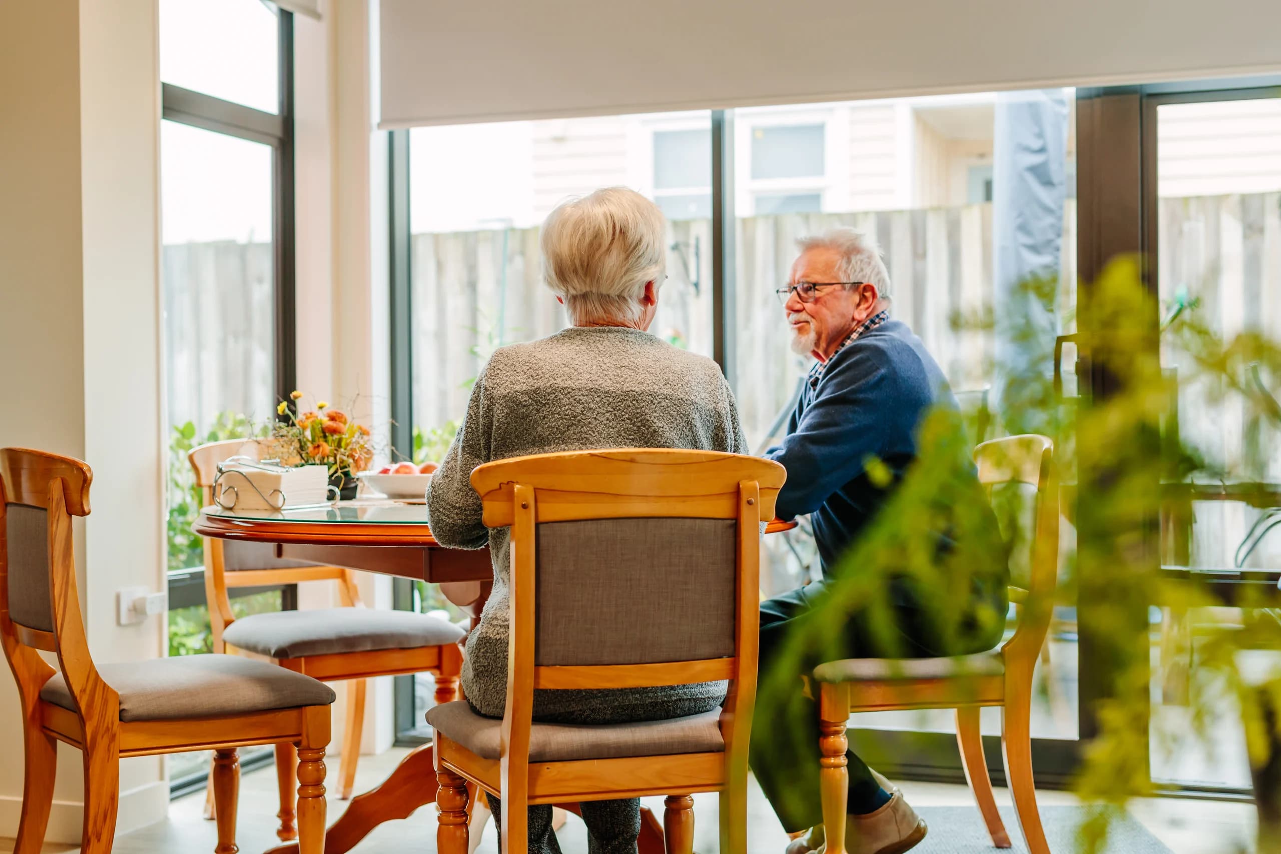 A couple chatting at a dining table in a bright living space