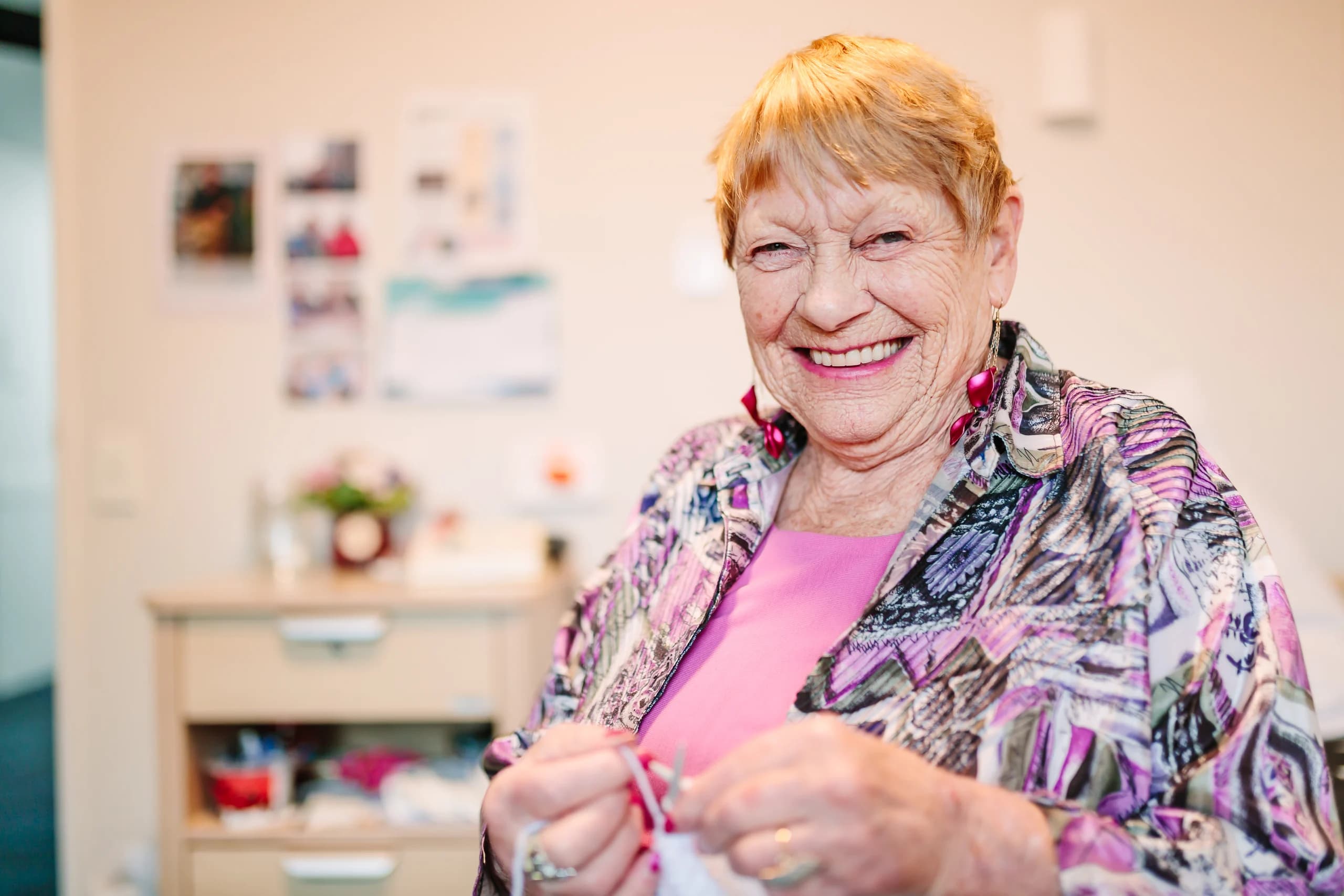 A resident enjoying knitting in a familiar setting