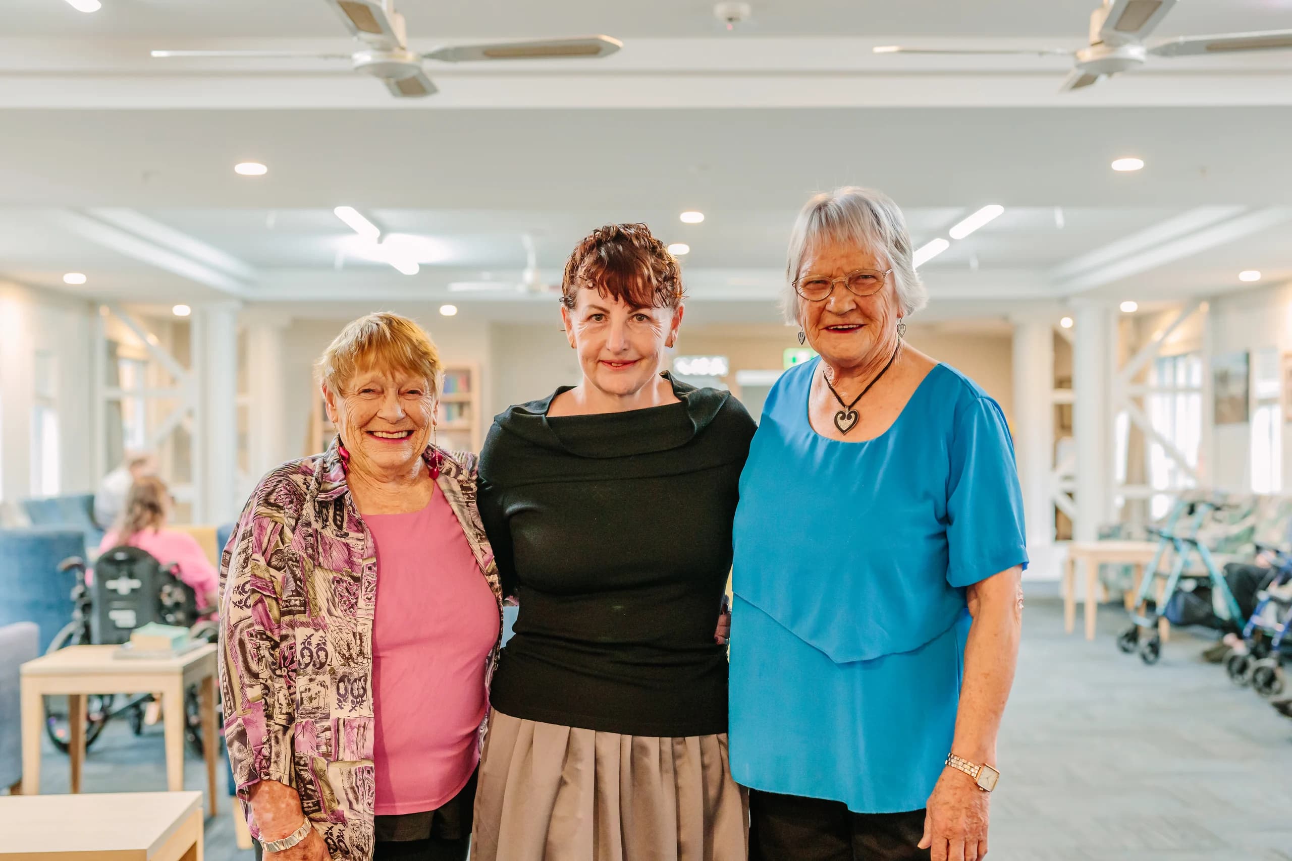 Three people smiling together in a community lounge